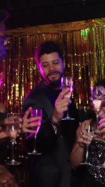 Kutlama yapan arkadaşlar, şenlikli bir atmosferde kadeh kaldırmak için şampanya kadehleri kaldıran yavaş çekim montajı yapan arkadaşlar.