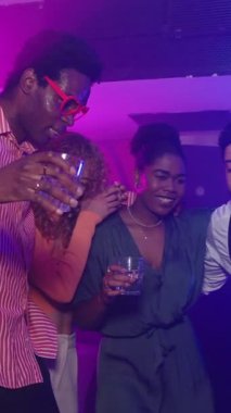 Mutlu çoklu etnik arkadaşlar içki ve müzikten keyif alıyorlar. Gece kulübü partisinde birlikte gülüp dans ediyorlar.