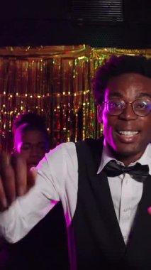 Enerjik genç garson, şenlikli gece kulübü atmosferinin tadını çıkarıyor, dans ediyor ve iş yerinde şampanyasını bulaşıcı bir neşeyle yudumluyor.