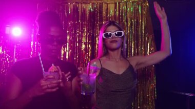 Gece kulübünde dans eden ve kokteyl içen genç kadınlar, yavaş çekim etkisiyle gece hayatının tadını çıkarıyorlar.