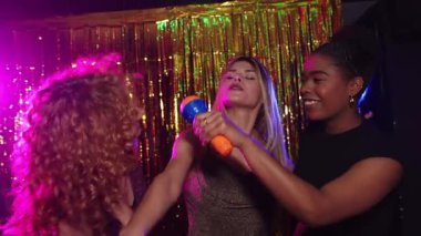 Arkadaşlar karaokeyi seviyor, renkli ışıklar ve ağır çekimde altın arka planla birlikte şarkı söylüyorlar.