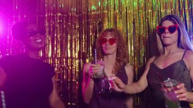 Genç kadınlar bir disko partisinde kokteyl içiyor, birlikte eğleniyor ve yavaş çekimde gülüyorlar.