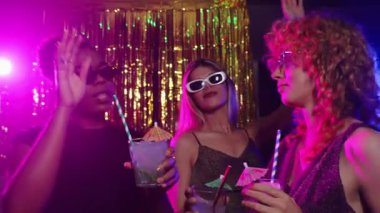 Çeşitli bayan arkadaşlar dans ediyor ve altın ışıkların altında renkli kokteyllerden zevk alıyorlar. Gece hayatı anlarını yavaş çekimde neşeli disko partileri sırasında paylaşıyorlar.