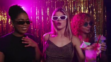 Bir disko partisinde dans eden ve kokteyl içen genç kadınlar, canlı bir yavaş çekim montajında çekildiler.