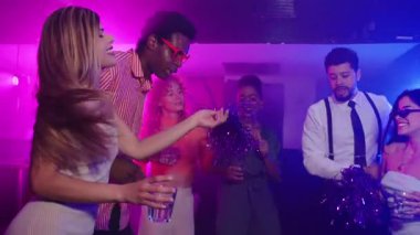 Genç yetişkinler bir gece kulübü partisinde dans edip içki içiyorlar. Ağır çekimde müzik ve atmosferin tadını çıkarıyorlar.