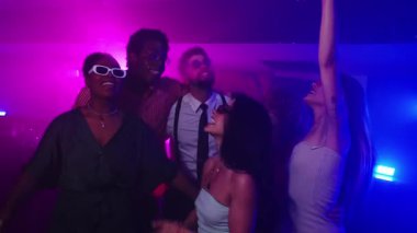 Genç insanlar neon ışıkları ve dumanlı bir kulüpte dans ediyor ve gece hayatından zevk alıyorlar, yavaş çekimde yakalandılar.