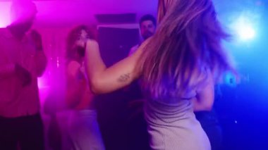 Enerjik grup canlı neon ışıkların altında dans ediyor, yavaş çekim video montajı ile dinamik gece kulüplerini yakalıyor genç kültürlerin neşeli ruhlarını ortaya çıkarıyor.