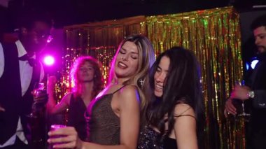 Büyüleyici bir partide dans eden ve gülen iki kadın, ağır çekimde müzik ve atmosferin tadını çıkarıyorlar.