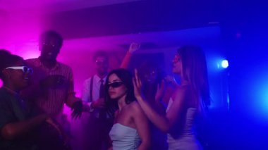 Yavaş çekim, renkli ışıklarla dans eden ve gece hayatının tadını çıkaran gençleri renkli bir kulüpte yakalıyor.