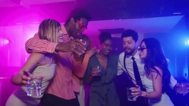 Mutlu arkadaşlar gece kulübünde renkli ışıklar altında dans edip içiyorlar, gece hayatının tadını çıkarıyorlar ve ağır çekimde kutluyorlar.