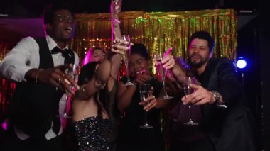 Neşeli arkadaşlar kadehlerini kaldırır, canlı bir fotoğraf kabini partisinde, büyüleyici bir yavaş çekim sahnesinde yakalanırlar.