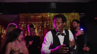 Bir partide dans eden ve içen bir grup zarif arkadaş, neşeli bir atmosferde birlikte eğleniyorlar, yavaş çekimde yakalanmışlar.