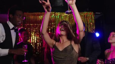 Çok ırklı arkadaşlar kutlama anlarını paylaşıyor, enerjik gece kulübü partisinde şampanyayla dans ediyor ve eğleniyorlar. Parlak bir geçmişi ve neşeli bir atmosferi var.