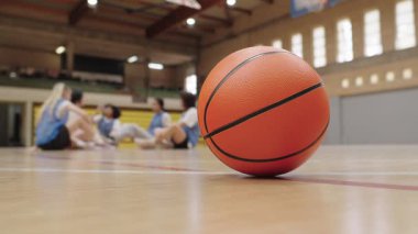 Basketbol sahasında dinleniyor, bayan oyuncular takım antrenmanı sırasında bulanık arka planda iyileşiyor.