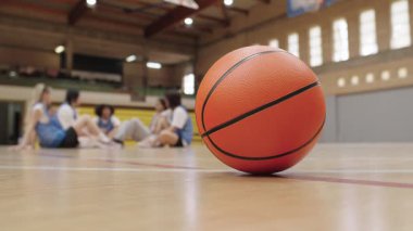 Basketbol sahasında dinlenme, basketbol takımının arka planda mola vermesi, yoğun antrenman ya da antrenman sırasında duraklama anı.