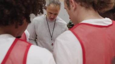 Mola sırasında basketbol koçu takımına rehberlik ediyor. Stratejik sezgilerini ve motivasyon liderliğini yoğun bir tartışma ortamında paylaşıyor.