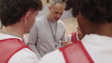 Basketbol koçu yoğun takım eğitimi sırasında genç sporculara tutkuyla rehberlik ediyor, iç sahada stratejik sezgileri ve motivasyonel liderliği paylaşıyor.