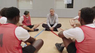 Basketbolcular, stratejik saha brifingi sırasında koçun taktik sezgilerini paylaşmasını dikkatle dinliyorlar. Takımları işbirlikçi öğrenme anında gösteriyorlar.