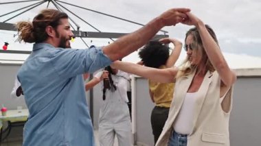 Arkadaşlar dans ediyor ve çatıdaki partide kutlama yapıyorlar. Neşeli anları içkilerle, müzikle ve güneşli gökyüzünün altında tasasız enerjiyle paylaşıyorlar.