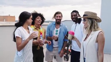 Çeşitli arkadaş grupları içki içerken, neşe ve kahkaha paylaşırken aynı zamanda panoramik şehir manzarasının tadını çıkarıyor.