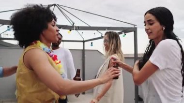 Cok uluslu arkadaslar dans ediyor, icki iciyor yaz aksamini yuksek enerjili ve kaygısız bir sekilde kutluyorlar.