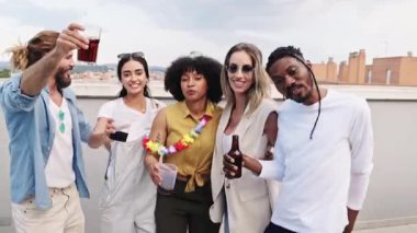 Neşeli çoklu etnik arkadaşlar kadehlerini kaldırıyor, içkinin tadını çıkarıyor ve çatıda kutluyorlar.