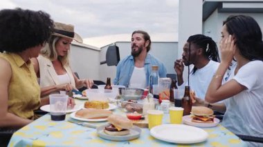 Cok kültürlü genç arkadaslar, canli yaz aksami boyunca kentin çatisinda içeceklerin tadini cikarip, sosyallesiyorlar.