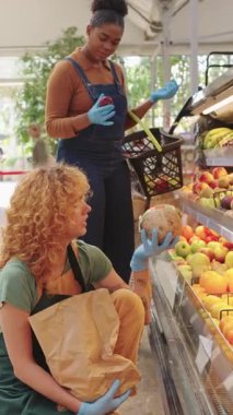 Koruyucu eldivenler giyen bakkal işçileri, Hindistan cevizi kalitesini yakından incelerken, yavaş çekim işyeri etkileşiminde tazelik ve seçilimi tartışıyorlar.