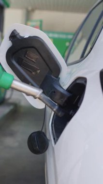 Yakından bir sürücünün yakıt pompasını beyaz bir araba deposuna sokması.