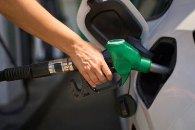 Yakından çekilen yeşil yakıt pompası hortumunu beyaz araba deposuna yerleştiriyor.