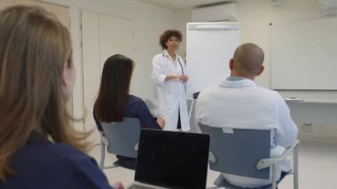 Doktorlar ve hemşireler hastane toplantı odasında bir tıp konferansına katılıp hasta bakımını tartışıyorlar.