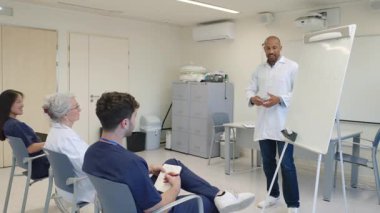 Doktorlar ve hemşireler hastane toplantı odasında bir tıp konferansına katılıp hasta bakımı stratejilerini tartışıyorlar.