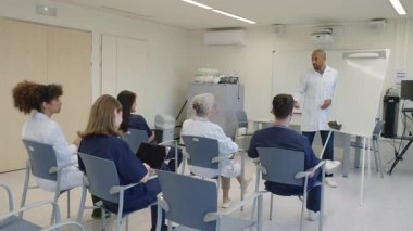 Hastane konferans odasında doktorun sunumuna katılan çeşitli tıbbi ekip, yavaş çekim.