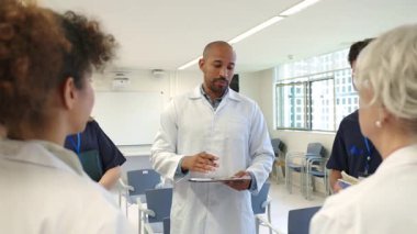 Doktorlar ve hemşireler yavaş çekim hastane toplantısında hasta bilgilerini ve tedavi planlarını gözden geçirirler.