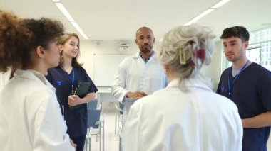 Tıbbi uzmanlar birlikte hasta vakalarını tartışıyor, ağır çekim hastane ortamında tedavi stratejileri geliştiriyor, uzmanlık ve takım çalışması sergiliyor.