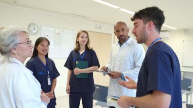 Tıbbi profesyoneller bir görüşme yapıyor, hastane toplantısı sırasında görüşlerini ve uzmanlıklarını paylaşıyorlar, yavaş çekimde çekiyorlar.