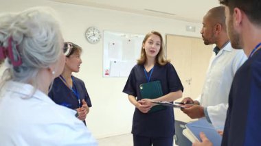 Hasta bakımını tartışan tıp uzmanları, fikir alışverişinde bulunurken, çizelgeleri analiz ederken ve ağır çekim hastane ortamında işbirliği yaparken,