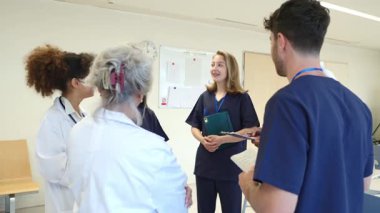 İşbirliği yapan, hasta çizelgelerini analiz eden ve modern hastane ortamında tedavi stratejilerini tartışan tıp uzmanları, takım çalışması ve uzmanlık gösterileri