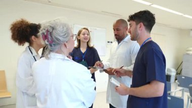 Hasta kayıtlarını yavaş çekimde inceleyen tıbbi ekip hastane ortamında profesyonel işbirliği gösteriyor.