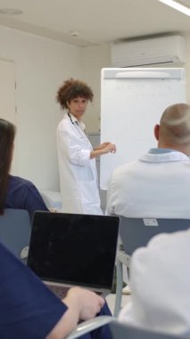 Tıp konferansında, bir doktorun ekibine hastane toplantı odasında sağlık ve aşılar hakkında bir sunum yaptığı görülüyor.