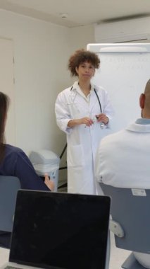 Doktor, hastane toplantı odasında yapılan sunum sırasında meslektaşlarına sağlık sistemini açıklıyor.