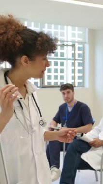 Kadın tıbbın önde gelen öğretici sunumu, parlak hastane konferans odasında sağlık görevlilerine hitap etmek, beyaz önlük giymek ve uzmanlığı paylaşmak.