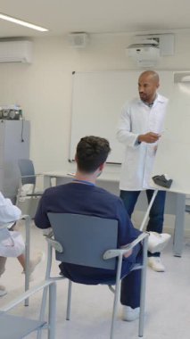 Tıp profesörü öğrenciler, hastane eğitim ortamında konferans sırasında beyaz tahtaya anahtar noktalar yazıyorlar.