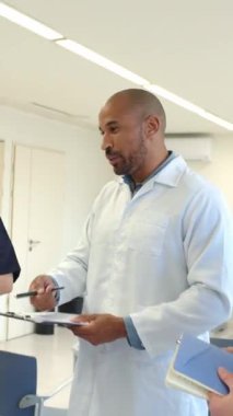 Doktor elinde dosya, hastane koridorundaki tıbbi personele teşhisi ağır çekimde açıklıyor.