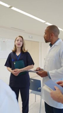 Tıbbi ekip hasta bilgilerini analiz ediyor, panodaki verileri dikkatle inceliyor ve bu sırada parlak, modern hastane ortamında işbirliği yapıyor.