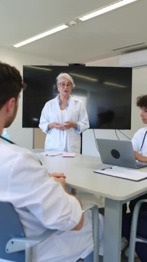 Experienced female doctor leading a medical briefing with her team in a modern hospital meeting room