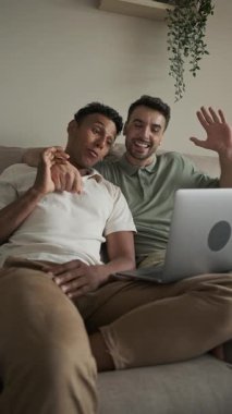 Sevecen lgbti partnerleri video çağrısı yoluyla bağlanıyor, sıcak sohbetleri paylaşıyor ve konforlu ev ortamından el sallıyor