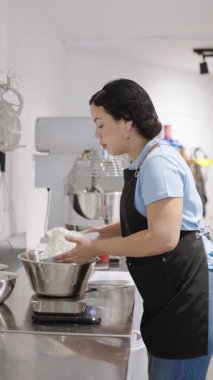 Fırıncı mutfak terazisine koyduğu una un ekliyor, pişirme malzemeleri hazırlıyor.