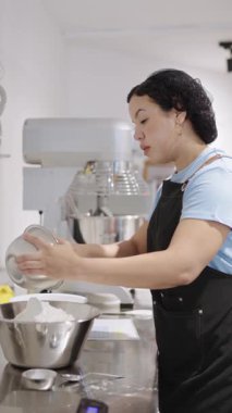 Profesyonel fırıncı ticari bir mutfakta karıştırma kabına un döküyor.