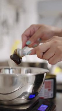 Mutfak terazisinde kaşıktan metal bir kaseye dökülen pekmez.